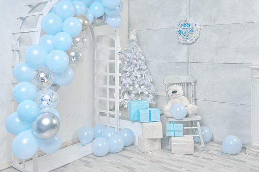 Christmas white and blue colors decor, wooden arch with balloons, white Christmas tree, studio shot