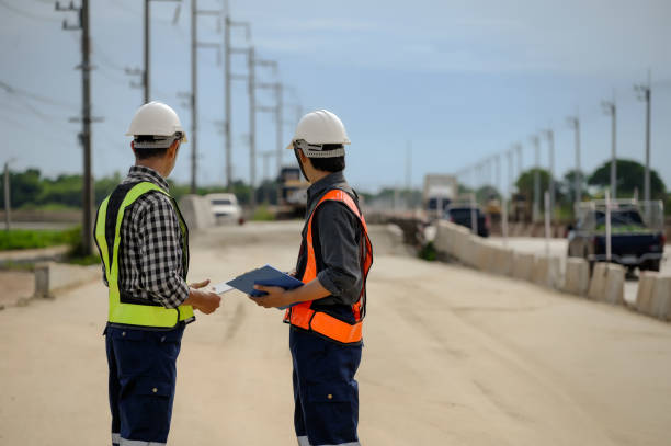 Highway engineers discuss plans for construction improvement based on roadworks. Soil Fill, Backfill Compaction for Sub base, Base Course, Surveyor Engineer inspector in highway construction. los ingenieros de carreteras discuten los planes para la mejora de la construcción basados en las obras viales. relleno de suelo, compactación de relleno para sub base, capa de base, ingeniero inspector topógrafo en construcción de carreteras.
