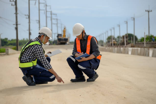 Highway engineers discuss plans for construction improvement based on roadworks. Soil Fill, Backfill Compaction for Sub base, Base Course, Surveyor Engineer inspector in highway construction. los ingenieros de carreteras discuten los planes para la mejora de la construcción basados en las obras viales. relleno de suelo, compactación de relleno para sub base, capa de base, ingeniero inspector topógrafo en construcción de carreteras.