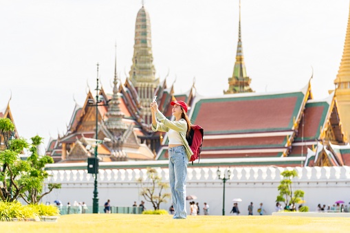 Holiday Joy in Bangkok. Asian Woman Solo Traveler Capturing Moments and Taking Selfies Outside Wat Phra Kaew and The Grand Palace
