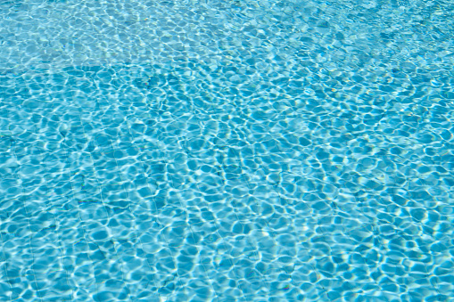 Swimming pool rippled water background, Blue swimming pool water with sun reflections