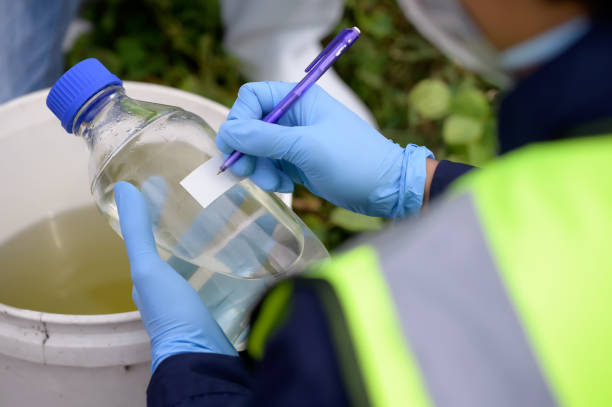 istock Environmental Engineers Team Take Water Samples at Natural Water Sources in a bottle. Water that smells bad Near Farmland May Be Contaminated by Toxic Suspicious Pollution Sites. 1919120060