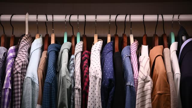 Hangers inside male wardrobe with many shirts and jackets