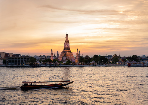 Sunset view of Wat Arun with a Boat Passing by the River