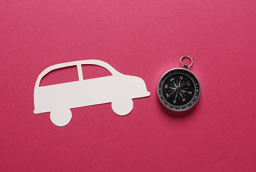 Paper-cut smartphone icon with compass on pink background. Navigation