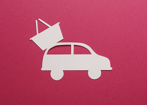 Paper-cut car icon with shopping basket on pink background