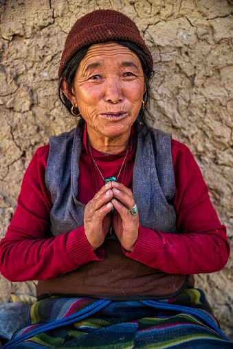 Tibetan woman saying namaste in small village in Upper Mustang. Mustang region is the former Kingdom of Lo and now part of Nepal,  in the north-central part of that country, bordering the People's Republic of China on the Tibetan plateau between the Nepalese provinces of Dolpo and Manang.