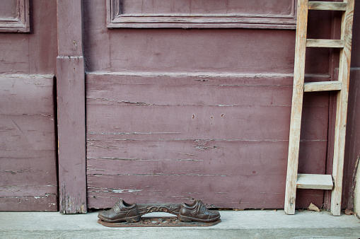 Detail of Small Shoes Sculpture and Staircase in Budapest City Center, Hungary, in front of a Wooden Old Door