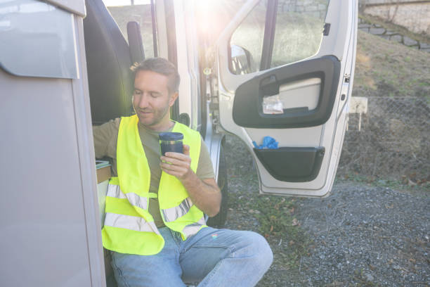 istock Delivery man on a break next to his tuck having coffee 1919204358