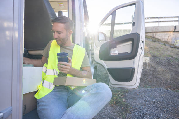 istock Delivery man on a break next to his tuck having coffee 1919204877