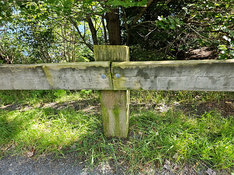 A closeup of a weathered wooden fence running along a hiking trail at the top of a hill to prevent people from falling down it.