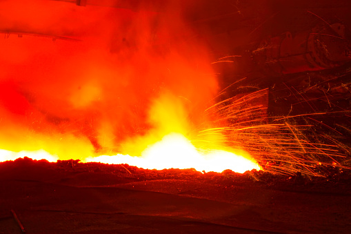 iron works blast furnace taphole spewing molten iron, closeup of photo