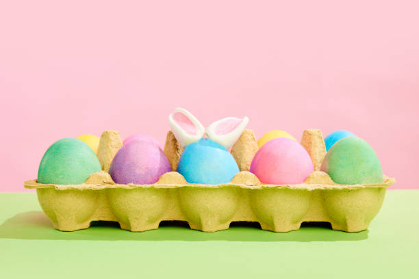 istock Multicolored painted Easter eggs on carton egg box isolated against pink background. Ester, holiday 1919213450