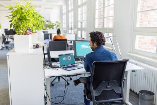 istock Young man busy working on laptop and desktop computer at office 1919243811