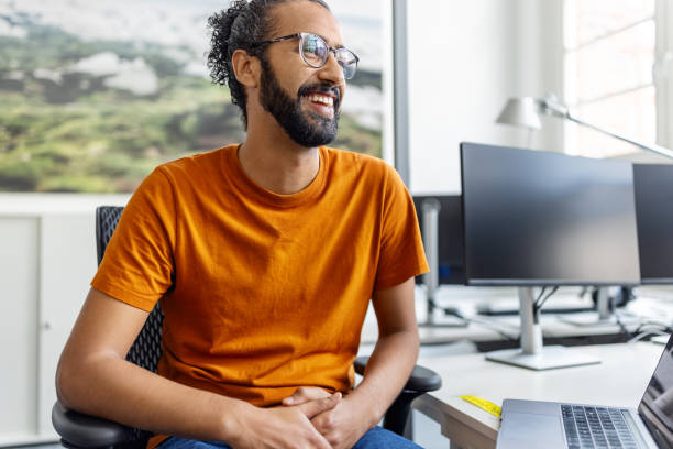 Happy young middle eastern man sitting at desk at office