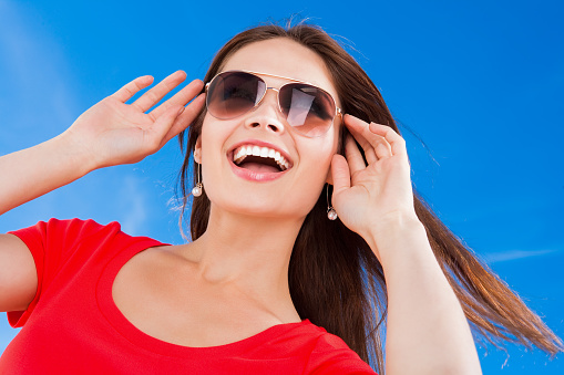 Beautiful Ukrainian female wearing sunglasses against blue sky