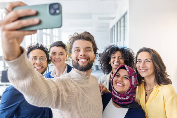 Happy group of creative workers taking a selfie at the office with a cell phone