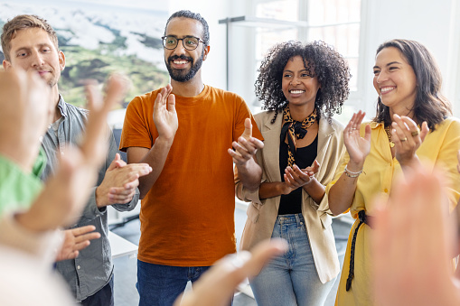 Multi-ethnic group of business people cheering in huddle. Business team clapping hands and celebrating success while standing together in a circle.