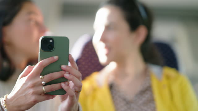 Women friends travelling by train using cell phone