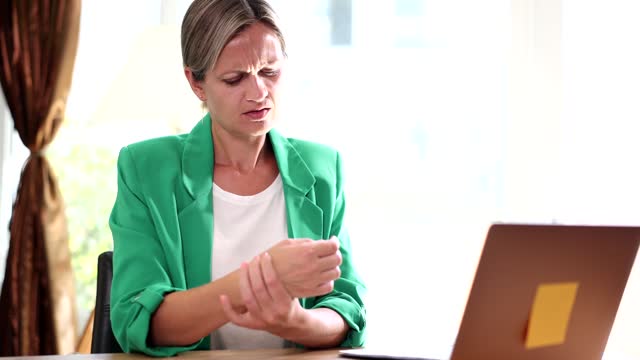 Closeup of woman holding wrist in pain from using computer