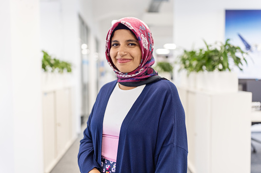 Portrait of happy middle eastern businesswoman at office. Woman executive wearing headscarf smiling at camera.