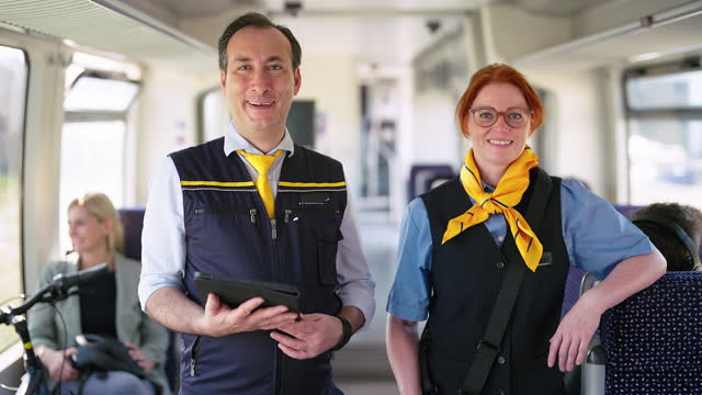 Portrait of two railway ticket checkers standing in train coach