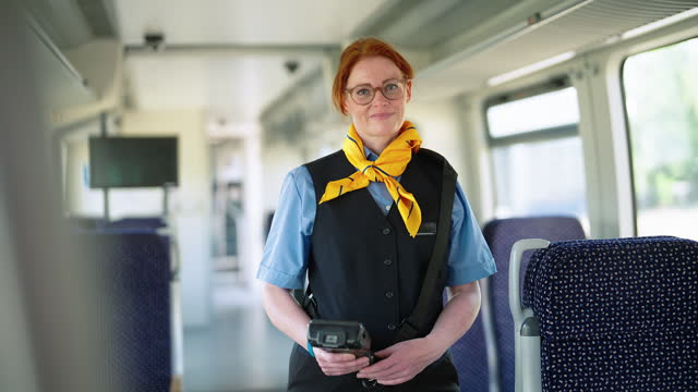 Woman railway conductor with ticket reader working on train