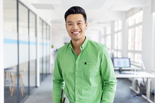 Portrait of smiling man entrepreneur in casuals standing at office. Businessman in creative office looking at camera and smiling.