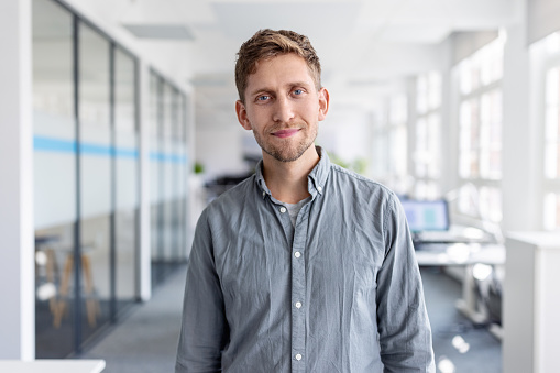 Portrait of businessman in office looking at camera. Confident male entrepreneur in casuals standing at office.