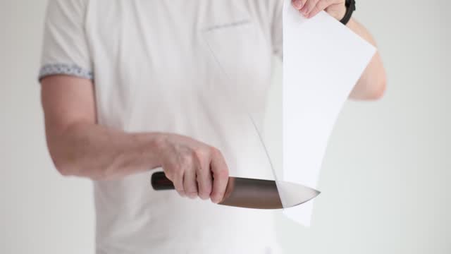 A man cuts paper with a sharp knife, close-up