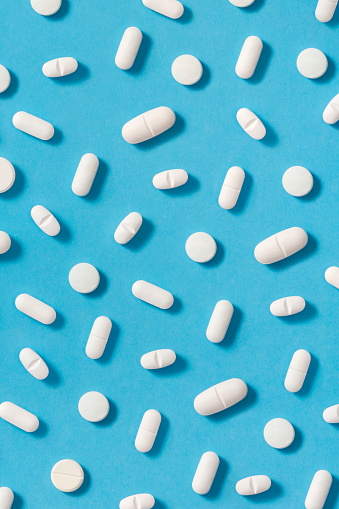 White pills on blue background with copy space