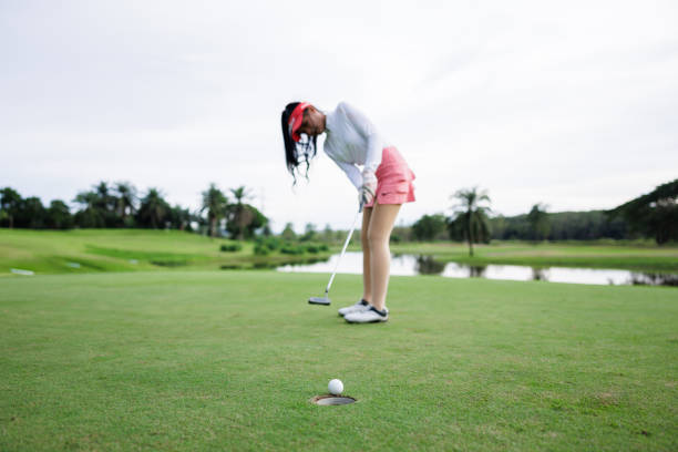 Professional young woman golfer teeing golf in golf tournament competition at golf course, selective focus on golf ball,