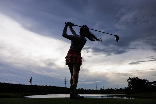 silhouette of professional young asian woman golfer practice in golf course,