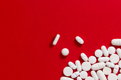 White pills on red background with copy space