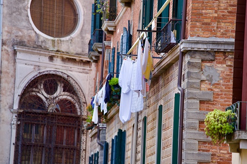 House facade with drying clothes on wire at City of Venice on a cloudy summer day. Photo taken August 6th, 2023, Venice, Italy.