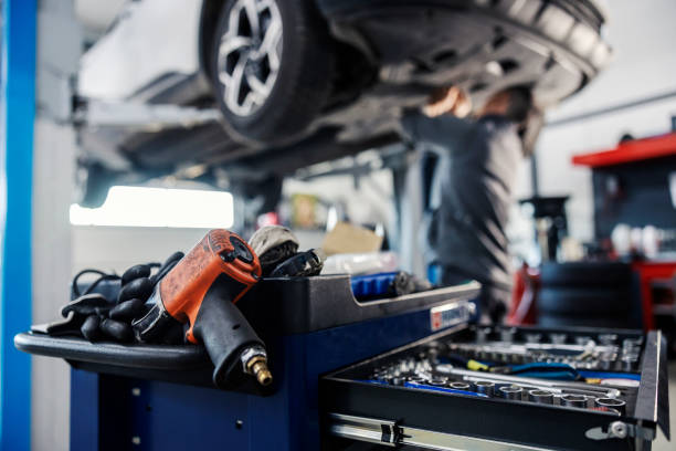 istock Selective focus on a drill and drawer with tools on a mechanic toolbox with worker fixing car in blurry background at mechanic's shop. 1919361179