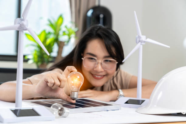 istock Young Asian woman with solar panel and light bulb, Solar energy concept. 1919377596
