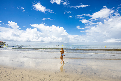 Woman walking in the empty beach in summer