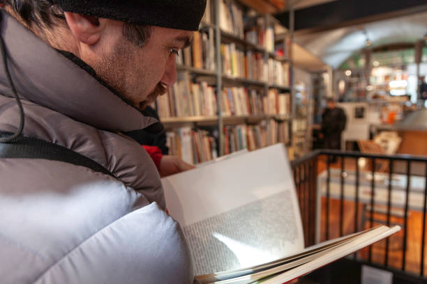 Man choosing a book from the shelf in the bookstore.