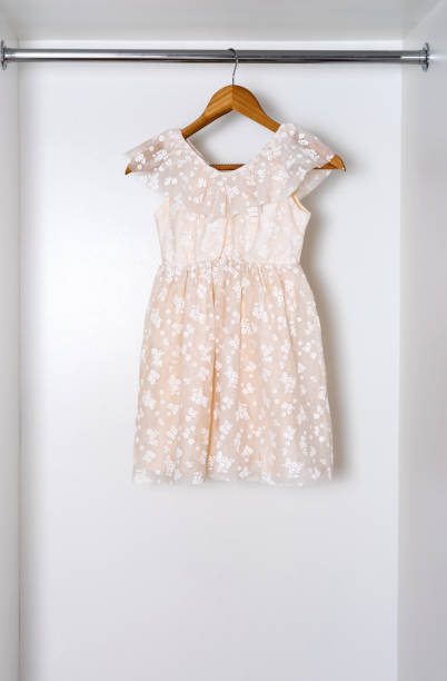 istock White children dress on hanger in white wardrobe. 1919446530