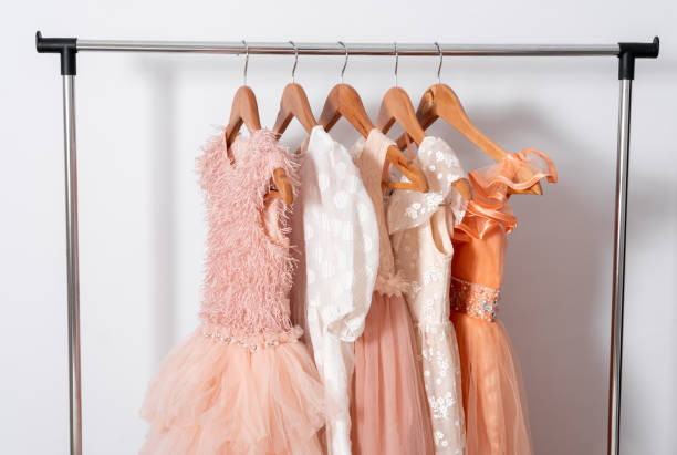 istock Puffy dresses hang on hanger on clothes rail on white wall background. 1919447056