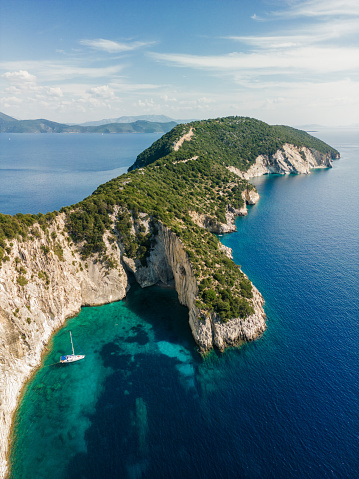 A sailboat anchored in a beautiful bay of Meganisi island in Greece. The sea is crystal clear, blue and turquoise.