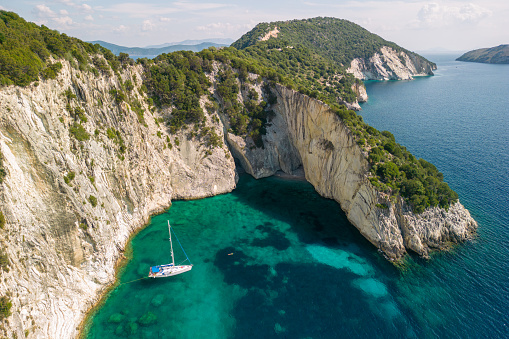 A sailboat anchored in a beautiful bay of Meganisi island in Greece. The sea is crystal clear, blue and turquoise.