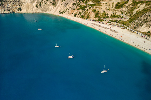 Sailboats and catamarans anchored in a beautiful bay of Myrtos beach, Kefalonia, Greece. The sea is blue and turquoise, it's a beautiful calm, sunny day.