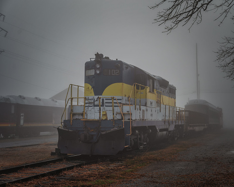 Kansas City, United States – December 23, 2023: A vintage train chugging its way through a dim, foggy rural landscape