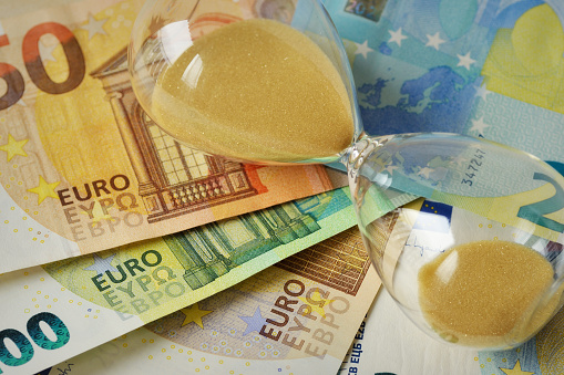 Close-up of hourglass lying on euro banknotes - Concept of time and money