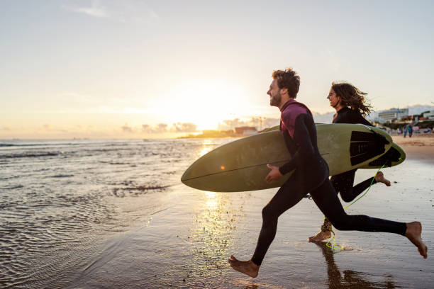 istock An excited couple rushing into the water with surfboards. 1919550126