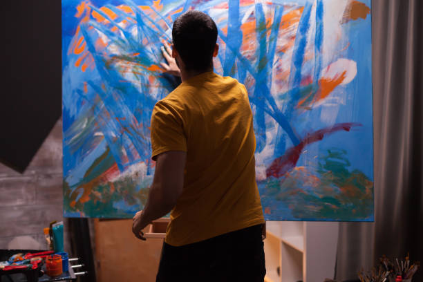 Artist working on painting in art workshop. Modern artwork paint on canvas, creative, contemporary and successful fine art artist drawing masterpiece