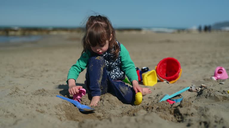 Little girl playing with sand in a spring warm day.