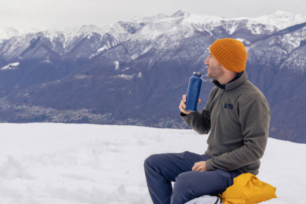 istock Male hiker taking a break, warming up with a hot drink 1919555434
